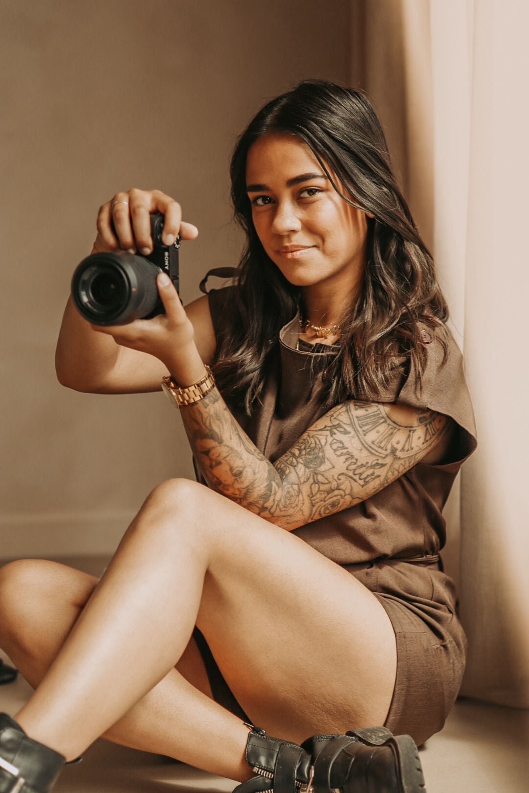 Christy zit op de grond met haar camera in de hand