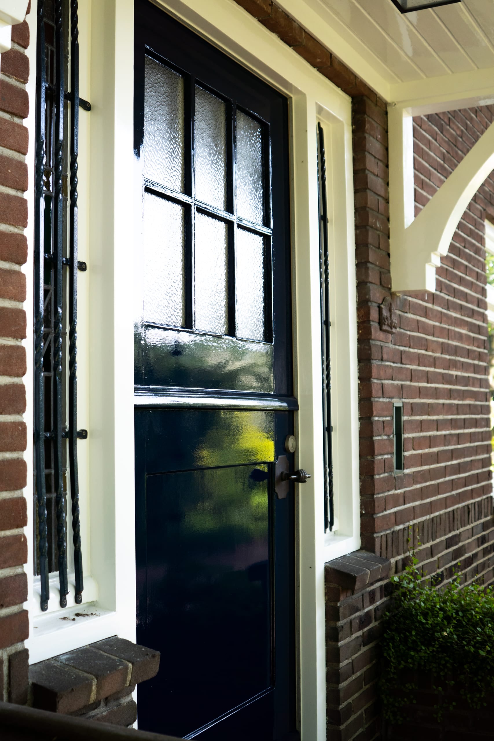 Zwart geschilderde voordeur van een woonhuis met sierlijk smeedwerk