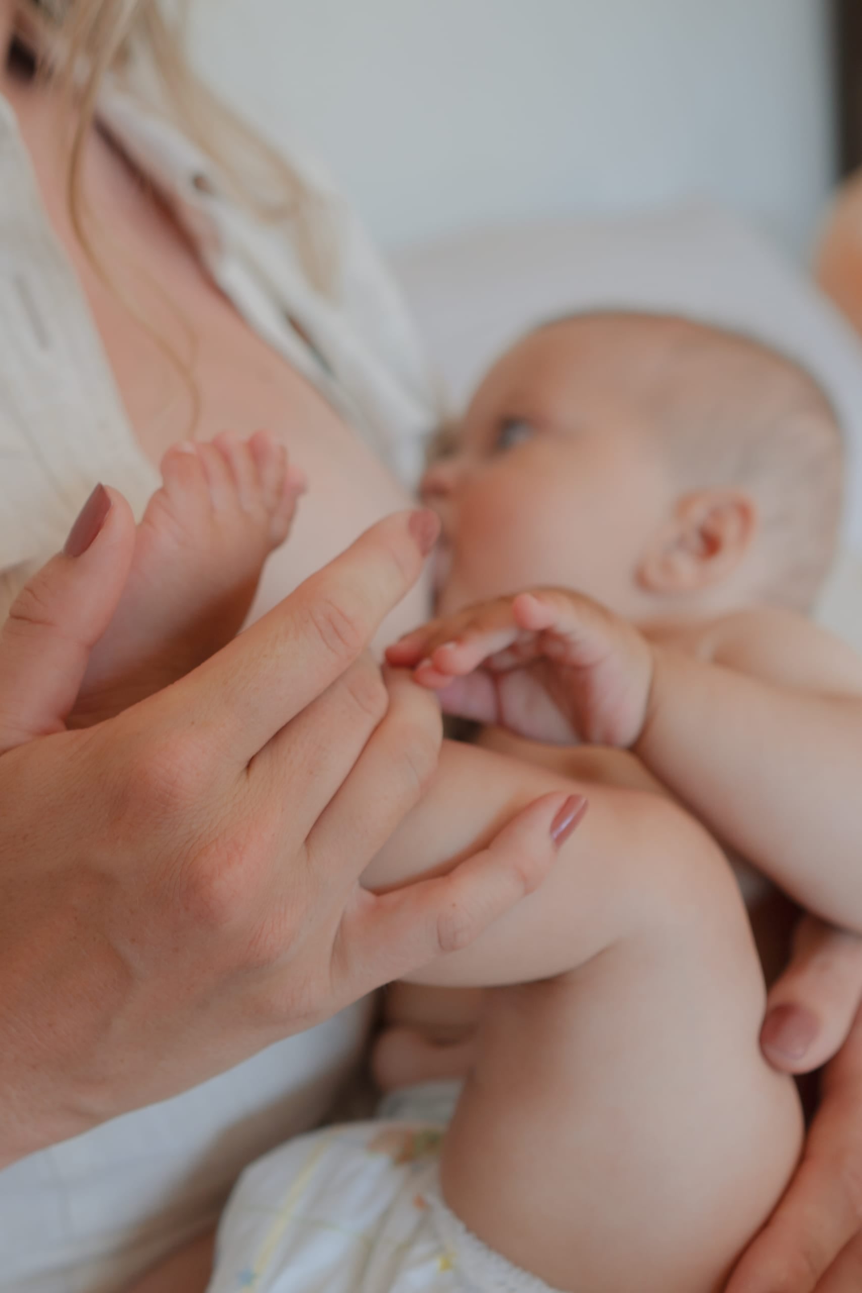Moeder voedt haar baby, de handjes van de baby om haar vinger